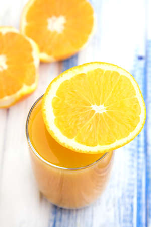 Glass of freshly pressed orange juice with sliced orange half on wooden tableの写真素材