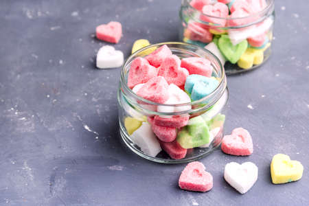 Jars with colored sugar in shape of heartの写真素材