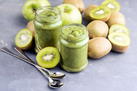 Two jars with green smoothie Kiwi and apple around jarsの写真素材