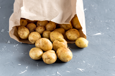 Young early potatoes in an old aluminum small bucket on a wooden background.の写真素材