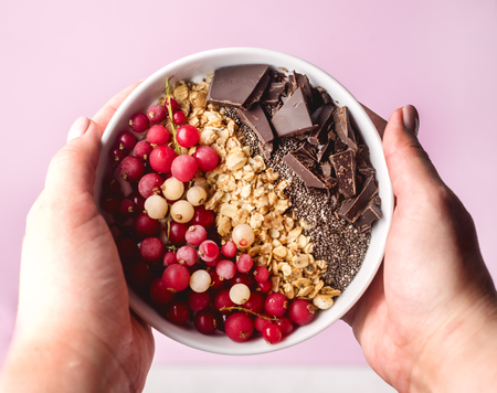 Female Hands Holding Bowl with Healthy Breakfast Smoothie with Granola Red Currant Chia Seed Dark Vegan Chocolate Diet Healthy Food Top Viewの写真素材