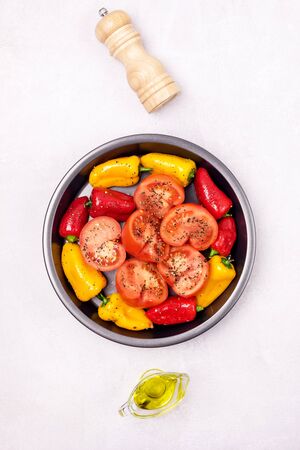 Ripe Tomato and Peppers Ready to Bake Vegetables on Black Plate Verticalの写真素材