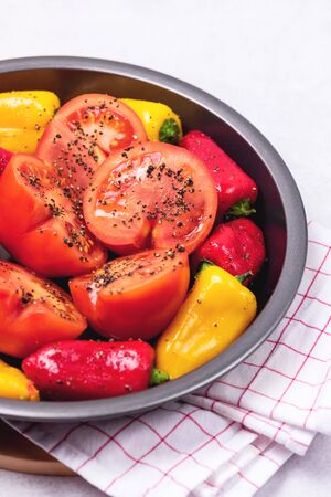 Ripe Tomato and Peppers Ready to Bake Vegetables on Black Plate Verticalの写真素材