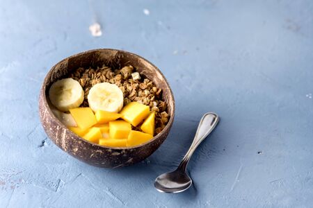 Granola With Yogurt Banana and Mango Tasty Healthy or Diet Breakfast Horizontal Copy Space Coconut Bowls Blue Backgroundの写真素材