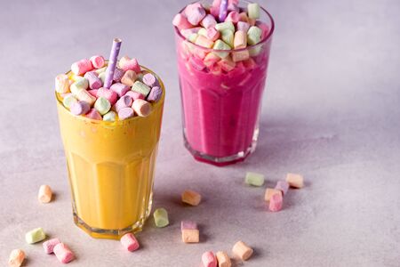 Two Glasses of Tasty Fruit Smoothies or Colored Milk Shake Decorated With Marshmallow Close Up Horizontalの写真素材