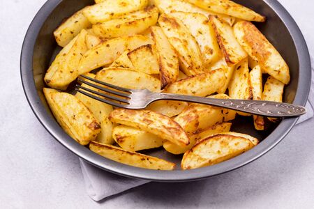 Roasted or Baked Potatoes With Spice in Black Bowl on Light Gray Background Tasty Homemade Dish Dinner Grilled Potatoesの写真素材