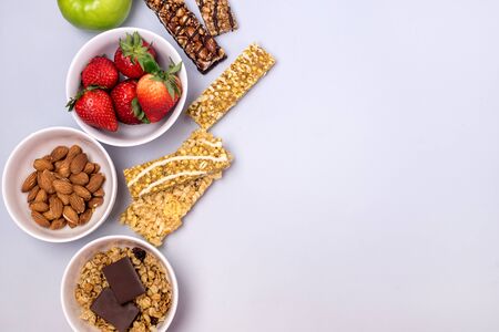 Bowls with Granola or Muesli Bowl with Strawberry and Almond Muesli Bars Blue Background Healthy Diet Breakfast Top View Flat Lay Copy Spaceの写真素材