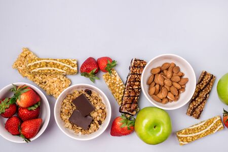 Bowls with Granola or Muesli Bowl with Strawberry and Almond Muesli Bars Green Apples Blue Background Healthy Diet Breakfast Top View Flat Layの写真素材