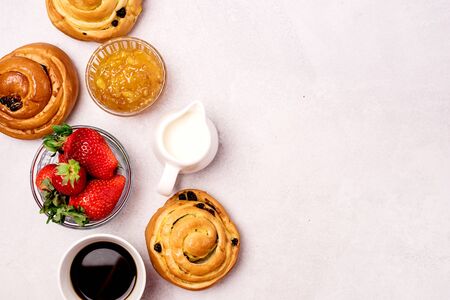Tasty Breakfast Freshly Baked Buns with Raisins and Cinnamon Cup of Black Coffee Cream Ripe Strawberry and Orange Jam in Glass Bowl Top View Copy Spaceの写真素材