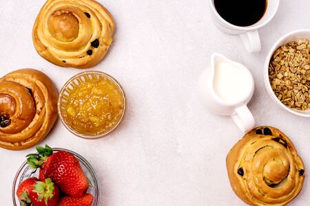 Tasty Breakfast Freshly Baked Buns with Raisins and Cinnamon Cup of Black Coffee Cream Ripe Strawberry and Orange Jam in Glass Bowl Top View Copy Space Frame Muesliの写真素材