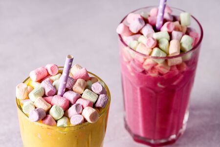 Two Glasses of Tasty Fruit Smoothies or Colored Milk Shake Decorated With Marshmallow Close Up Horizontalの写真素材