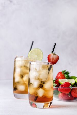 Glasses of Cold Citrus and Strawberry Ice Tea on Light Gray Background Decorated with Ripe Lime and Strawberry Healthy Symmer Beverage Refreshing Drink Verticalの写真素材