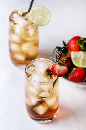 Glasses of Cold Citrus and Strawberry Ice Tea on Light Gray Background Decorated with Ripe Lime and Strawberry Healthy Symmer Beverage Refreshing Drink Aboveの写真素材