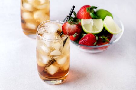 Glasses of Cold Citrus and Strawberry Ice Tea on Light Gray Background Decorated with Ripe Lime and Strawberry Healthy Symmer Beverage Refreshing Drinkの写真素材