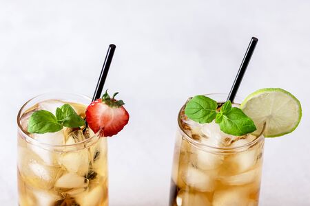 Glasses of Cold Citrus and Strawberry Ice Tea on Light Gray Background Decorated with Ripe Lime and Strawberry Healthy Symmer Beverage Refreshing Drink Close upの写真素材