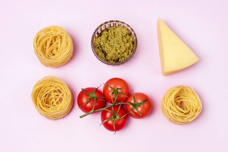 Dry Raw PastaTagliatelle Pesto Parmesan Cheese Raw Tomato Top View Pink Background Top Viewの写真素材