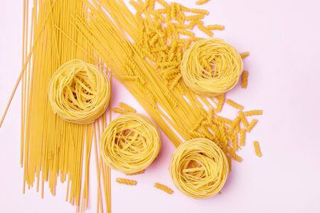 Raw Dry Pasta Spaghetti Tagliatelle Fusilli Italian Food Pink Background Top Viewの写真素材