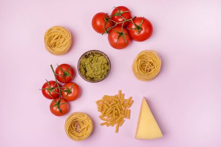 Dry Raw PastaTagliatelle Pesto Parmesan Cheese Raw Tomato Top View Pink Background Top Viewの写真素材