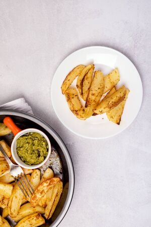 Roasted or Baked Potatoes With Spice in Black Bowl on Light Gray Background Tasty Homemade Dish Dinner Grilled Potatoes Verticalの写真素材