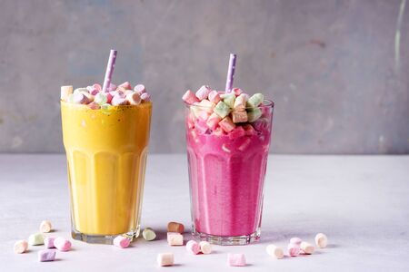 Two Glasses of Tasty Fruit Smoothies or Colored Milk Shake Decorated With Marshmallow Close Up Horizontalの写真素材