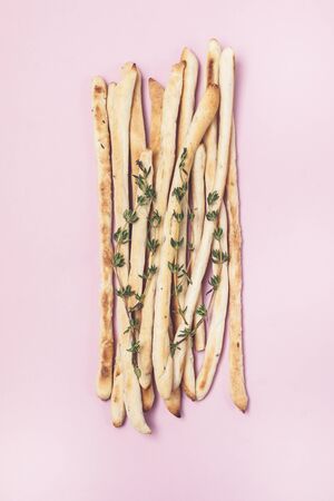 Homemade Cheese or Bread Sticks with Herds Crispy Bread Sticks with Thyme and Rosemary on Pink Background Top View Horizontalの写真素材