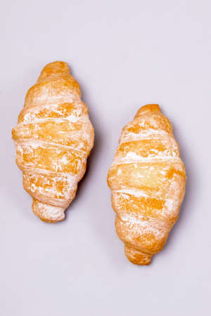 Two Fresh and Tasty Croissants on a Pink Plate Blue Background Top View Vertical