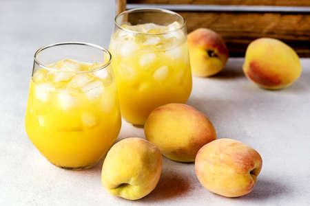Ripe Peaches Tasty and Cold Peaches Juice Healthy Drink with Ice Cube Gray Background Horizontalの写真素材