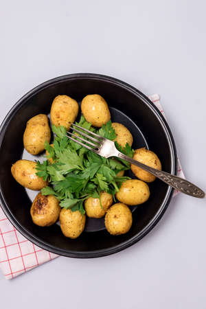 Organic Young Roasted Potatoes on Black Plate Decorated with Parsley Top View Verticalの写真素材
