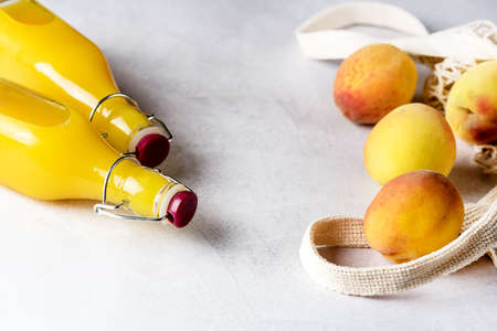 Natural Peach Juice in a Bottle and Eco Bag with Ripe Peaches Gray Background Healthy Diet Drink Horizontal Frameの写真素材