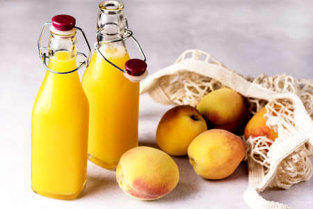 Natural Peach Juice in a Bottle and Eco Bag with Ripe Peaches Gray Background Healthy Diet Drink Horizontalの写真素材