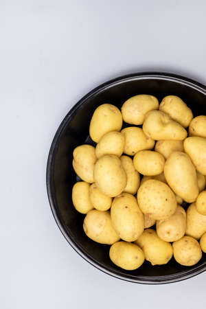 Black Plate of Raw Young Potatoes on Blue Background Top View Verticalの写真素材