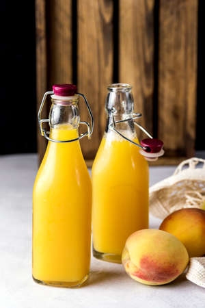 Natural Peach Juice in a Bottle and Eco Bag with Ripe Peaches Gray Background Healthy Diet Drink Verticalの写真素材