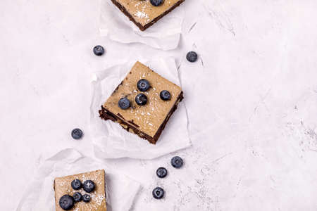 Pieces of Homemade Chocolate Brownies Decorated with Ripe Blueberry on Gray Background Tasty Chocolate Dessert Copy Spaceの写真素材