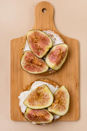 Canape or Crostini with Toasted Baguette Cream Cheese and Figs on Wooden Board Delicious Appetizer Lunch Yellow Background Top Viewの写真素材