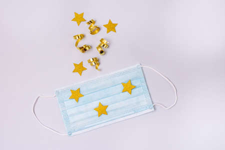 Gold Confetti in Shape of Star Protective Face Mask on Blue Background New Year 2021 Celebration...