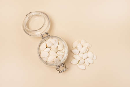 Glass Jar of Dried Pumpkin Seed on Light Yellow BackgroundTop View Horizontalの写真素材
