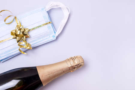 Bottle of Champagne Present Protective Face Mask on Blue Background New Year 2021 Celebration Concept Top view Flat lay Pandemic Holidays Copy Spaceの写真素材