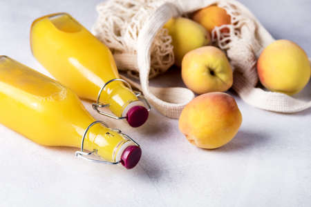 Natural Peach Juice in a Bottle and Eco Bag with Ripe Peaches Gray Background Healthy Diet Drink Horizontalの写真素材