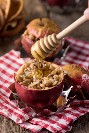 Tasty Homemade Baked Apple with Cinnamone Honey and Huts Healthy Seasonal Autumn or Winter Dessert Wooden Background Verticalの写真素材