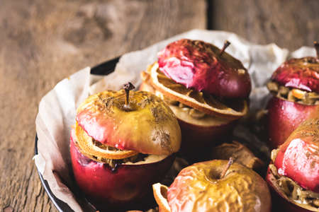 Homemade Oven Baked Apples Stuffed with Nuts Orange Chips and Honey in Baking Pan Old Wooden Background Healthy Autumn or Christmas Dessert Horizontalの写真素材
