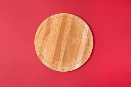 Wooden Round Empty Board or Tray for Pizza on a Red Background Horizontal Top Viewの写真素材