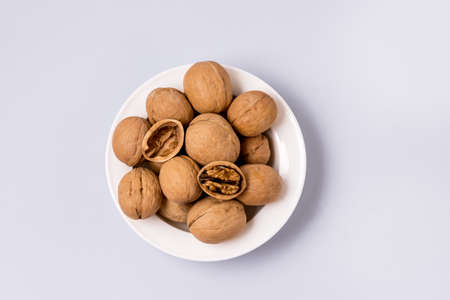 White Bowlof Walnut Kernels and Whole Walnuts on Blue Background Top View Horizontalの写真素材
