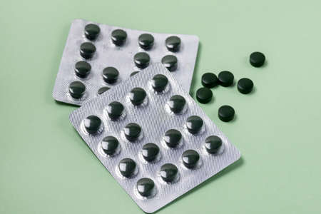 Blisters of Spirulina Tablets on Green Background Super Food Horizontalの写真素材