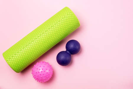 Foam Roller and Ball Roller Fitness Equipment Pink Background Myofascial Release MFR Female Hand Holds a Roller Relax and Fitness Conceptの写真素材