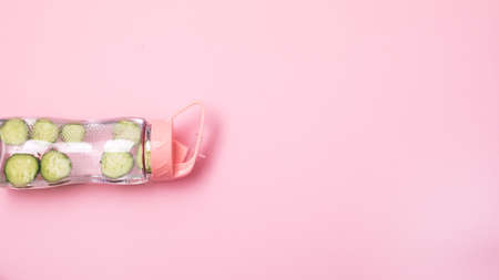 Bottle of Infused water with cucumbe on Pink Background Horizontal