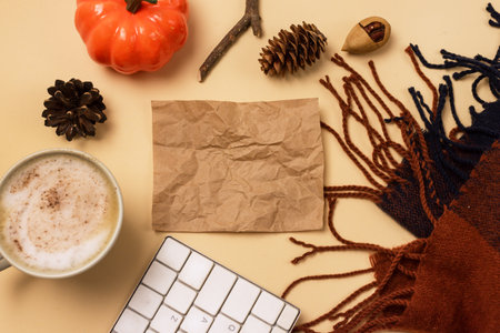 Warm Scarf Cup of Coffee Notebook or Keyboard Pumpkin Pine Cone Cozy Autumn Background or Concept Top View Blogger Conceptの写真素材