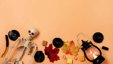 Halloween Holiday Background with Skeleton Halloween Candy Leaves View From Above Orange Background Bannerの写真素材