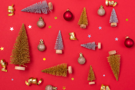 Small Gold and Silver Christmas Tree Gold Christmas Balls Gold Confetti on Red Background Christmas Background or Card Top Viewの写真素材