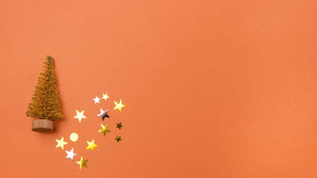 Lovely Fake Mini Christmas Tree and Golden Confetti on Orange Background Banner Little christmas tree Copy Spaceの写真素材