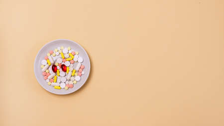 White Plate with Vitamin or Tablet on Yellow Backgroundの写真素材